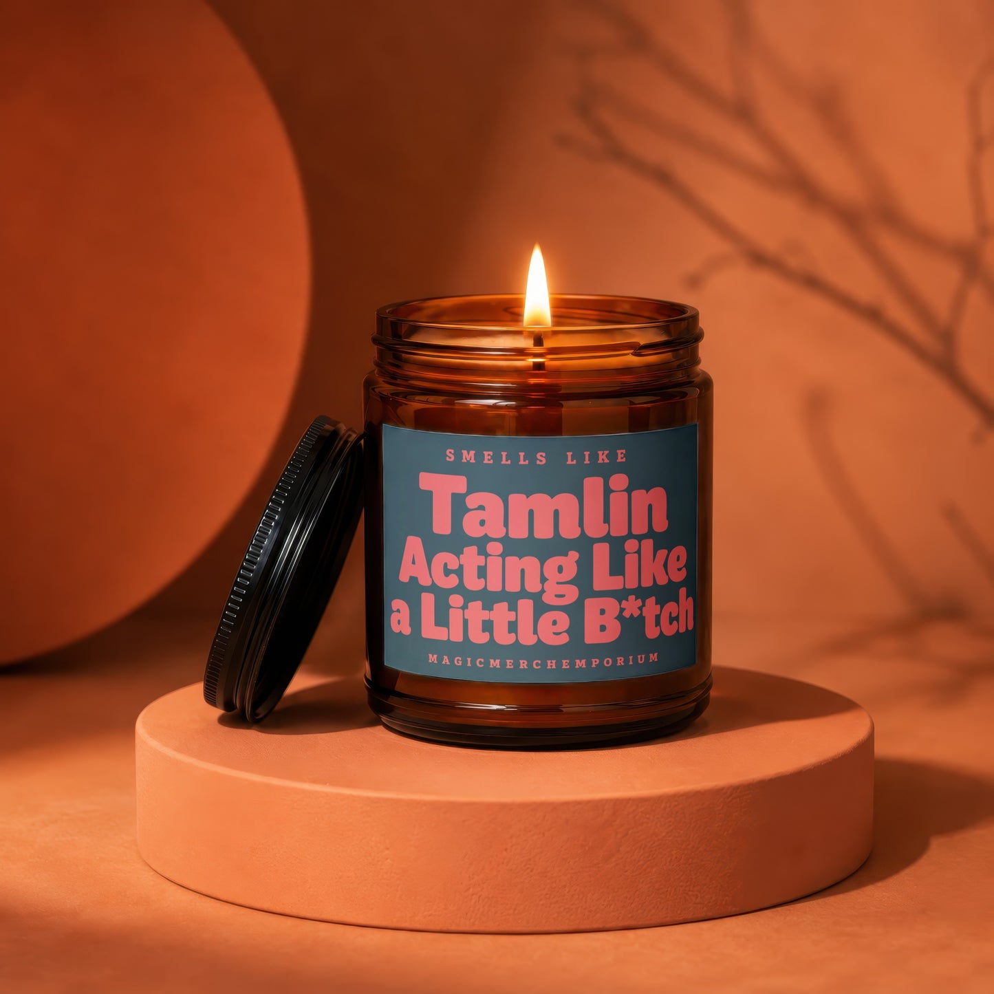 Candle with a lit wick and a label that reads "Smells Like Tamlin Acting Like a Little B*tch".