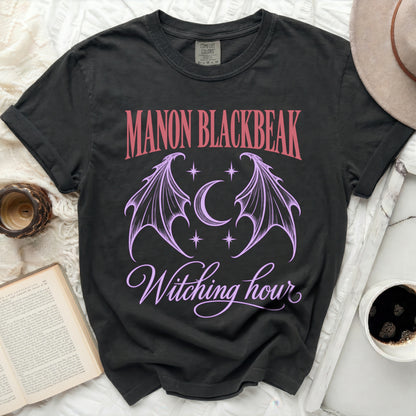 Black Comfort Colors t-shirt with "MANON BLACKBEAK Witching hour" text and gothic wings design.