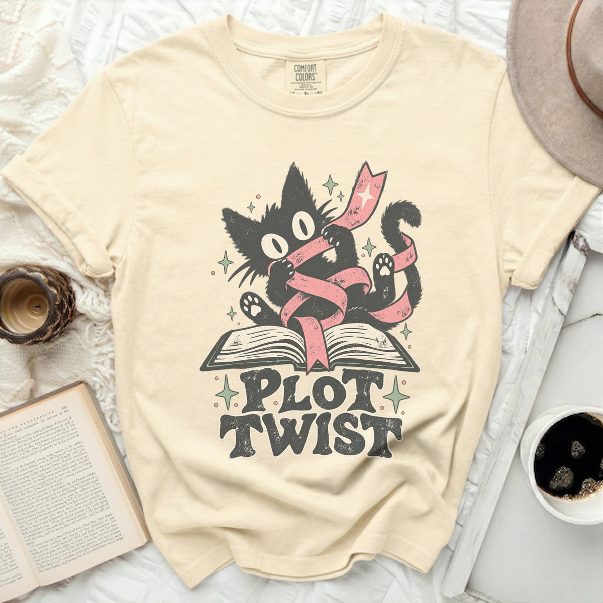 Black cat with pink ribbon on open book, text reads "PLOT TWIST."