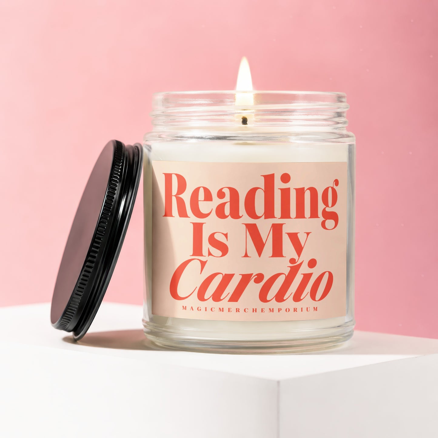 Lit candle in glass jar with "Reading Is My Cardio" text and black lid.