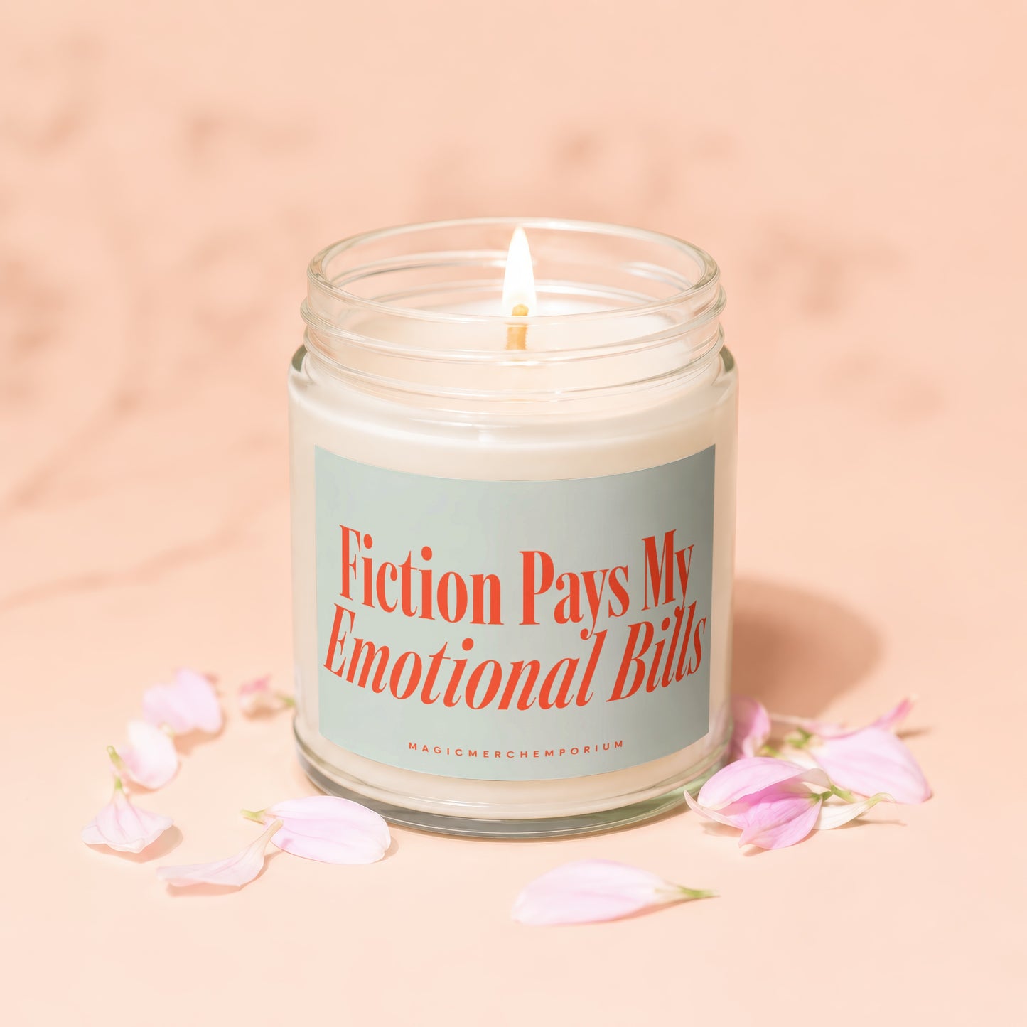 Candle with lit wick and label that reads "Fiction Pays My Emotional Bills."