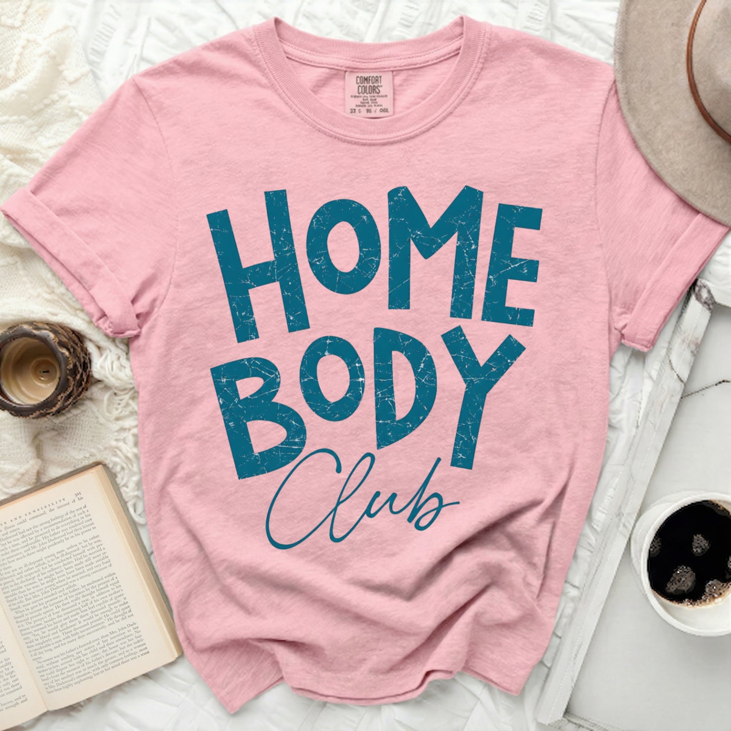 Pink t-shirt with "HOME BODY Club" text in distressed teal letters.