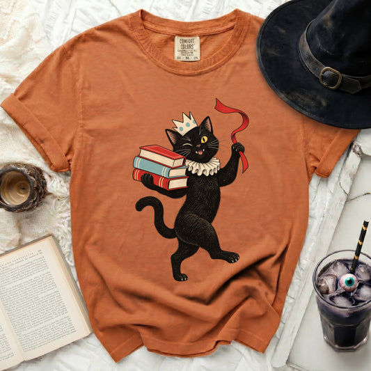 Black cat wearing a crown and ruff, holding books and ribbon.