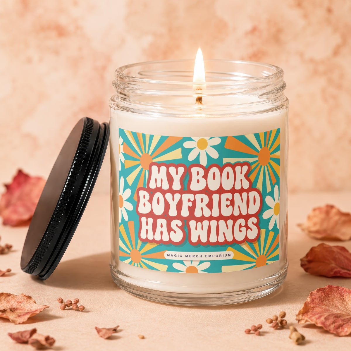 Glass candle with lit wick and label that reads "My Book Boyfriend Has Wings."