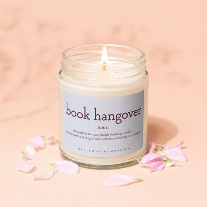 Lit candle in glass jar with "book hangover" definition label and pink petals.