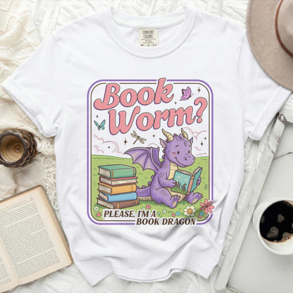 White t-shirt with a graphic of a purple dragon reading a book, text reads "Book Worm? Please, I'm a Book Dragon."
