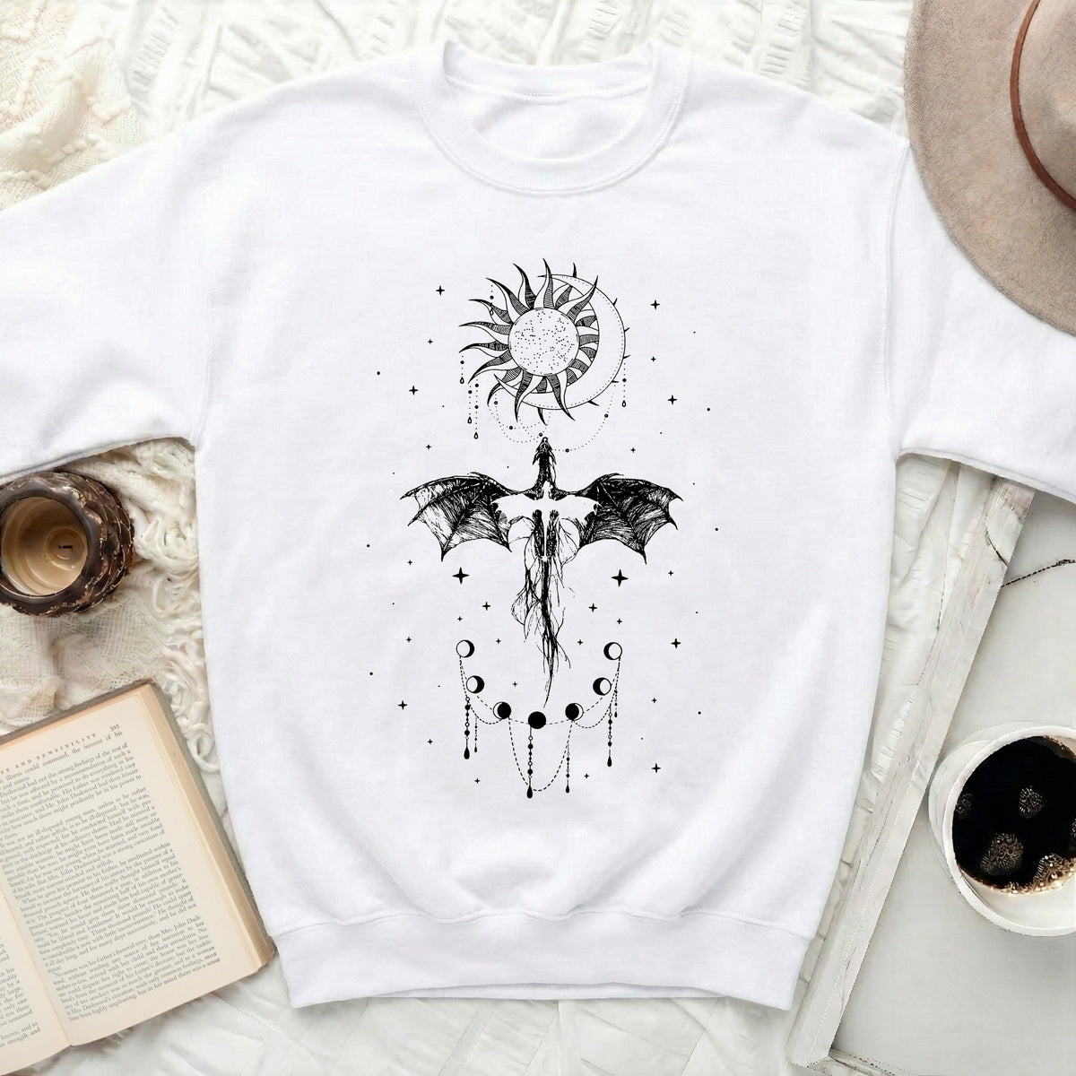 White crewneck sweatshirt with black dragon, sun, moon, and stars graphic.