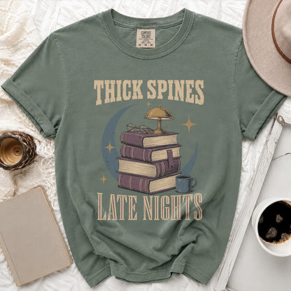 Green t-shirt with "THICK SPINES LATE NIGHTS" text and stack of books graphic.