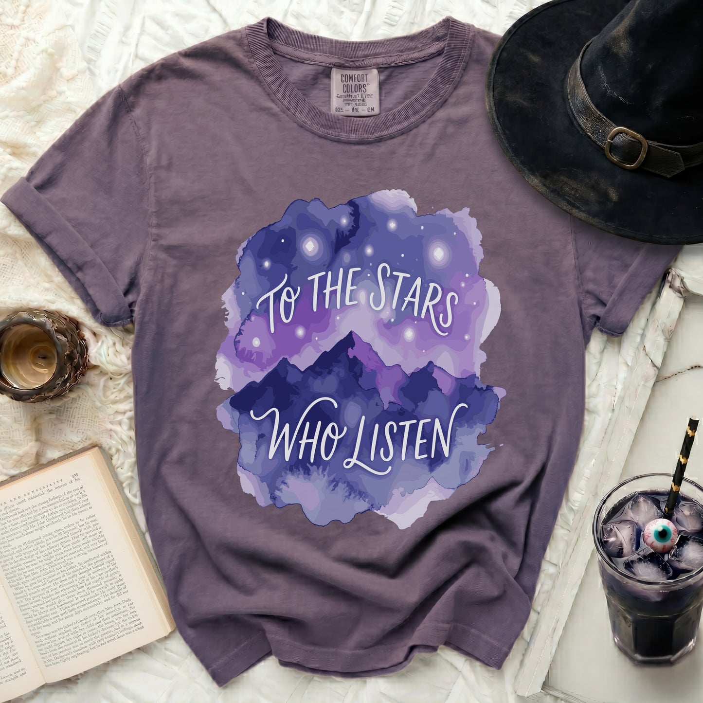 Purple t-shirt with "To the Stars Who Listen" graphic and starry mountains.