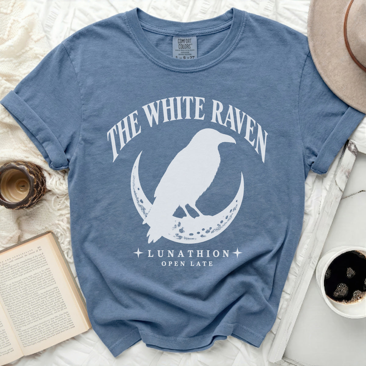 Blue t-shirt with white raven on moon graphic and text "The White Raven Lunathion Open Late".