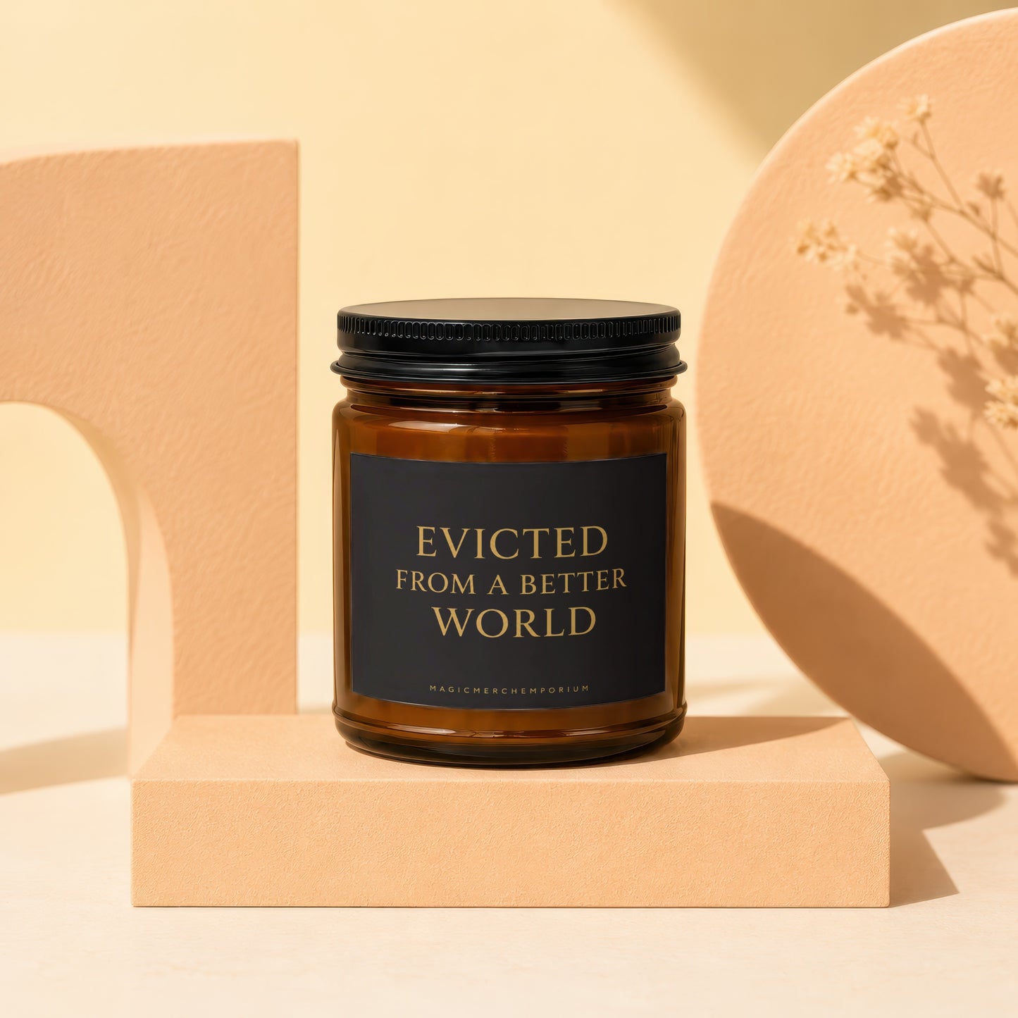 Brown glass candle with black lid and label reading "EVICTED FROM A BETTER WORLD".