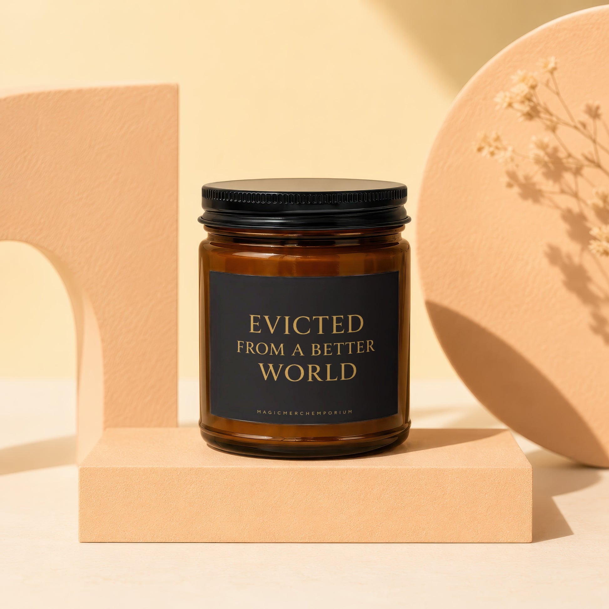 Brown glass candle with black lid and label reading "EVICTED FROM A BETTER WORLD".