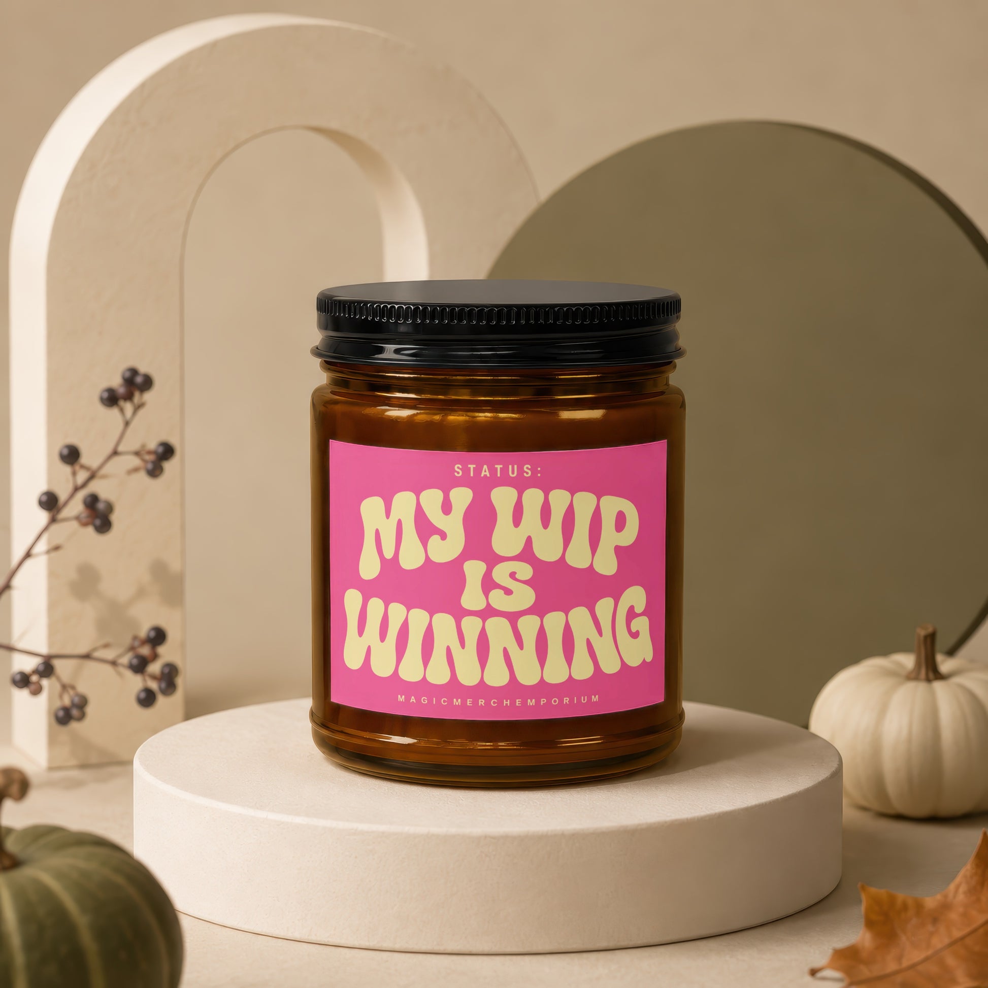 Amber jar candle with pink label reading: "STATUS: MY WIP IS WINNING"