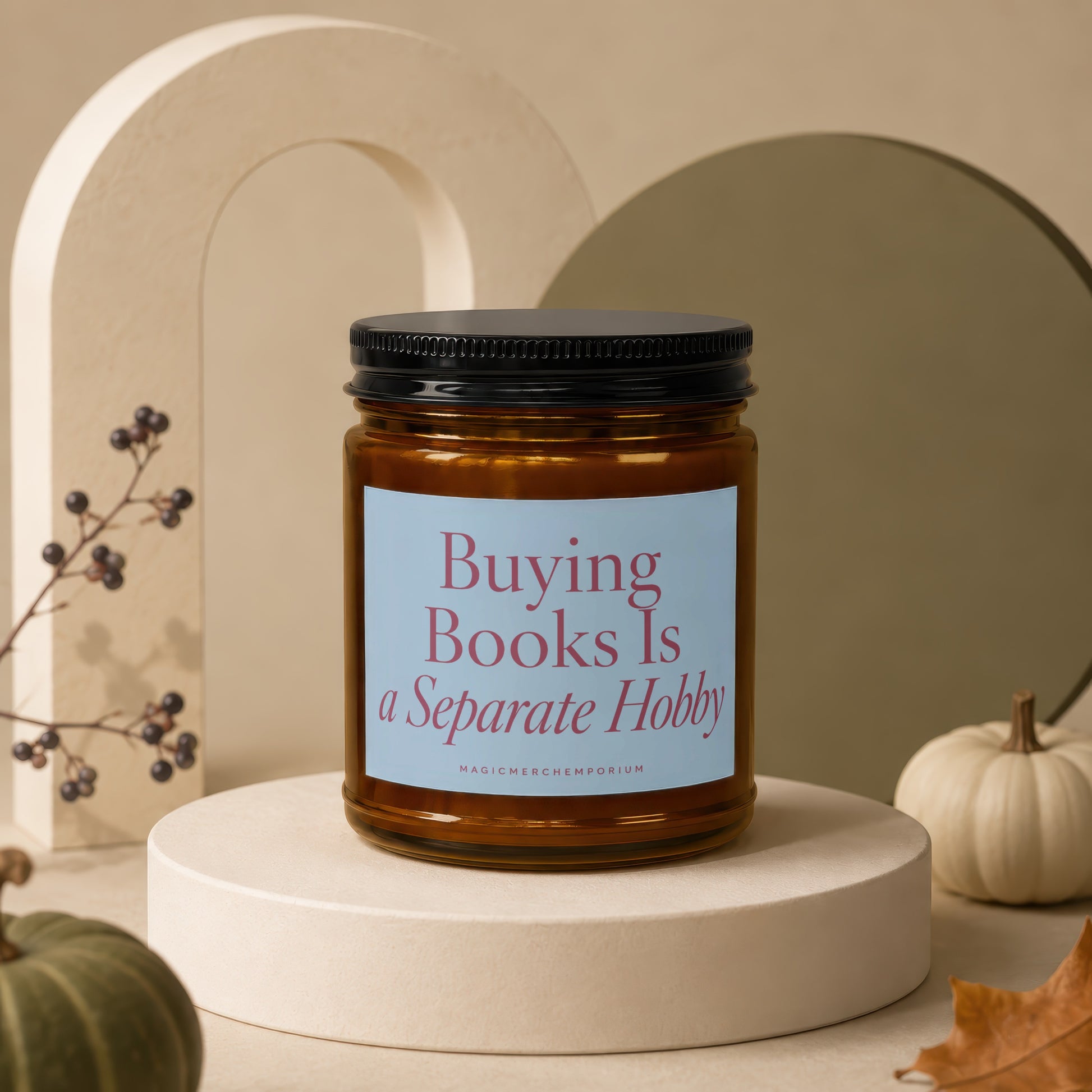 Amber candle with black lid labeled "Buying Books Is a Separate Hobby".