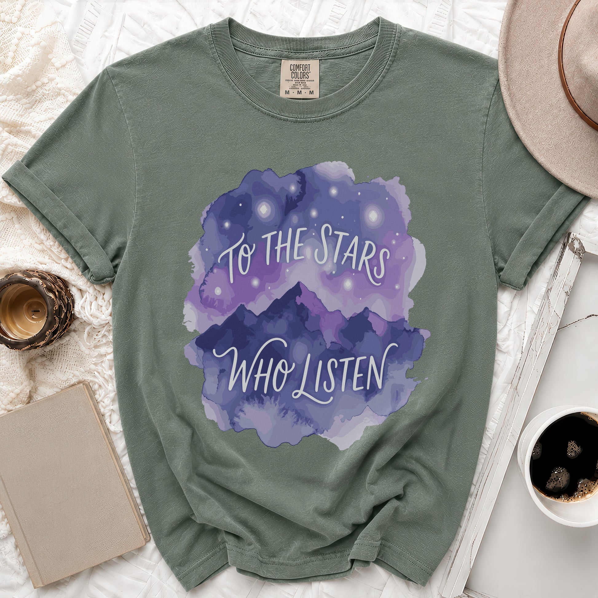 Olive green t-shirt with purple watercolor mountains and stars graphic that reads "To The Stars Who Listen".