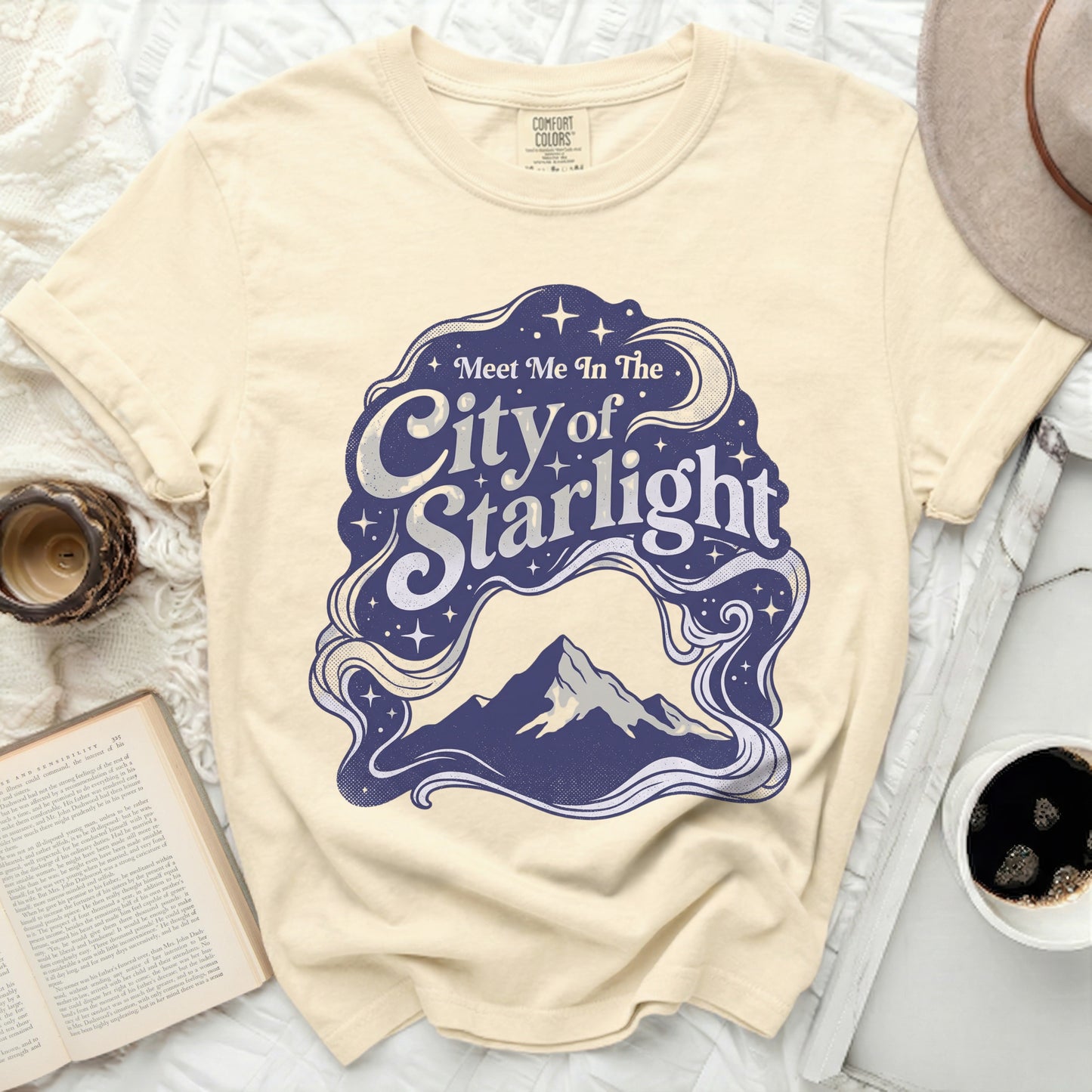 Cream t-shirt with "Meet Me In The City of Starlight" graphic.
