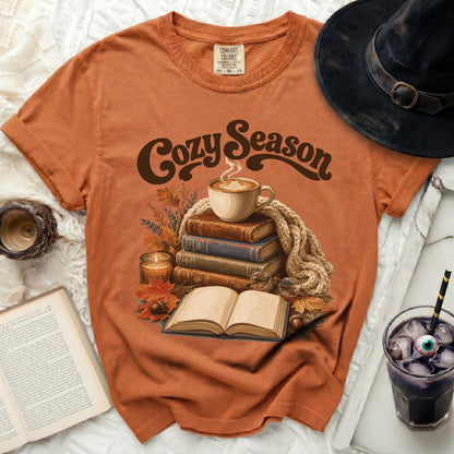 Orange t-shirt with "Cozy Season" text above stacked books and coffee.