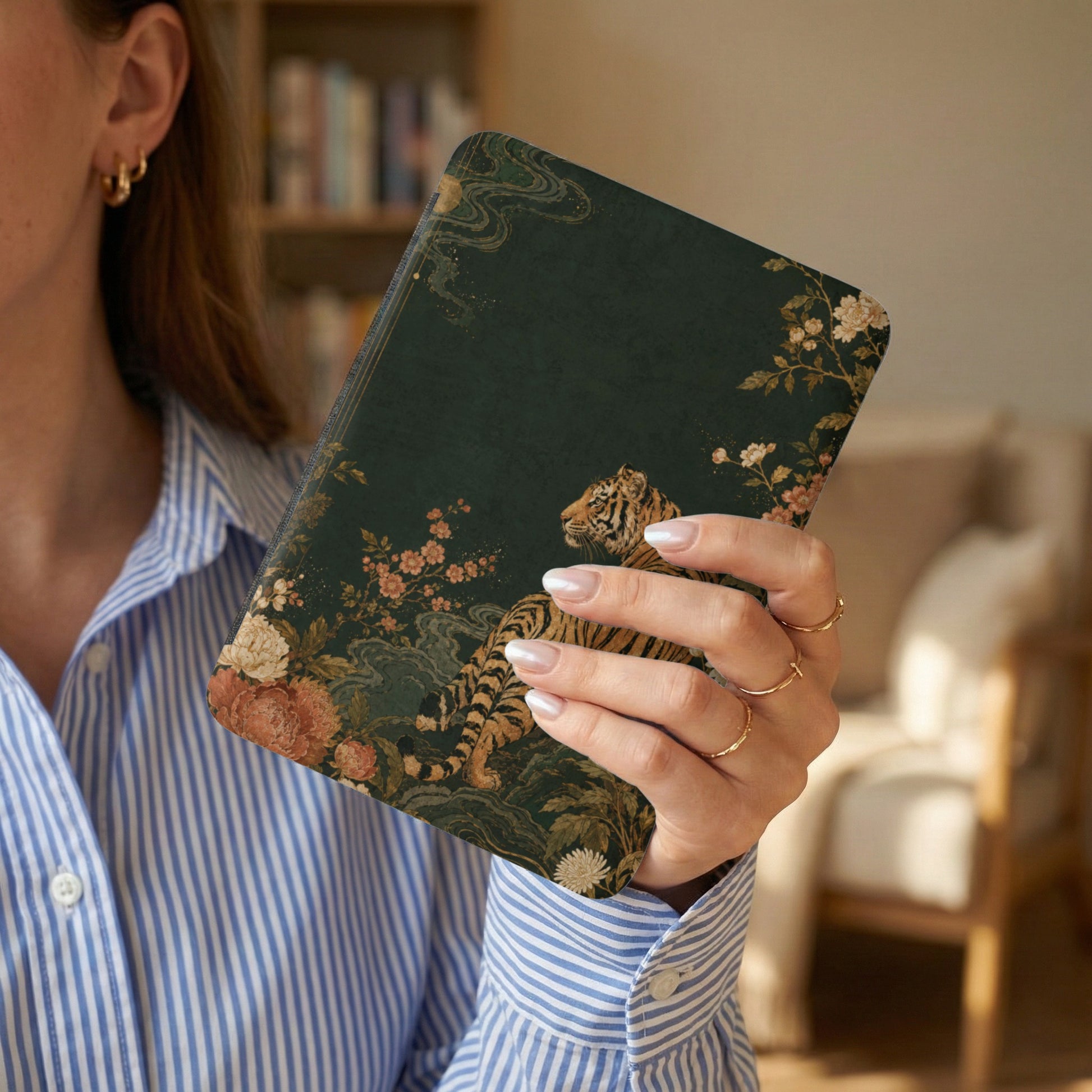 Journal with a tiger and floral design held by a person wearing a striped shirt.