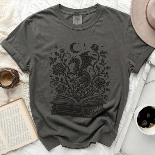 Grey t-shirt with a black dragon moon and roses graphic on an open book.