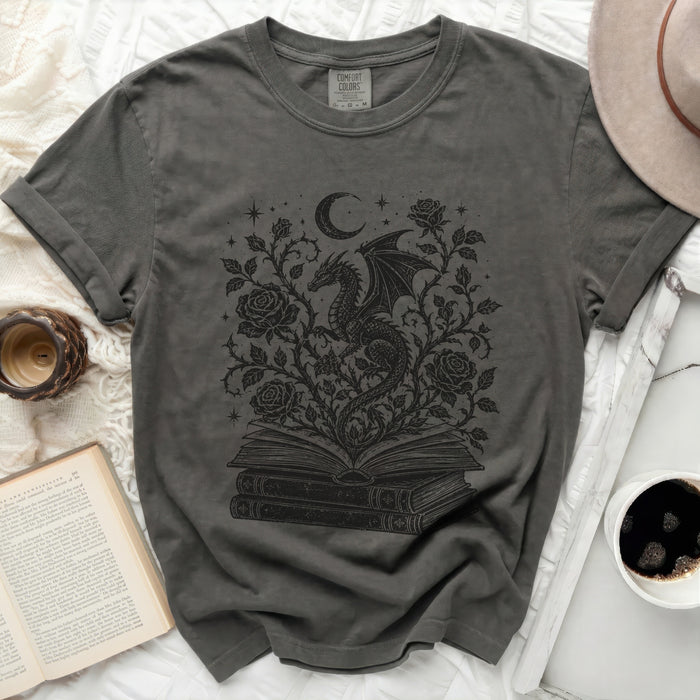 Grey t-shirt with a black dragon moon and roses graphic on an open book.