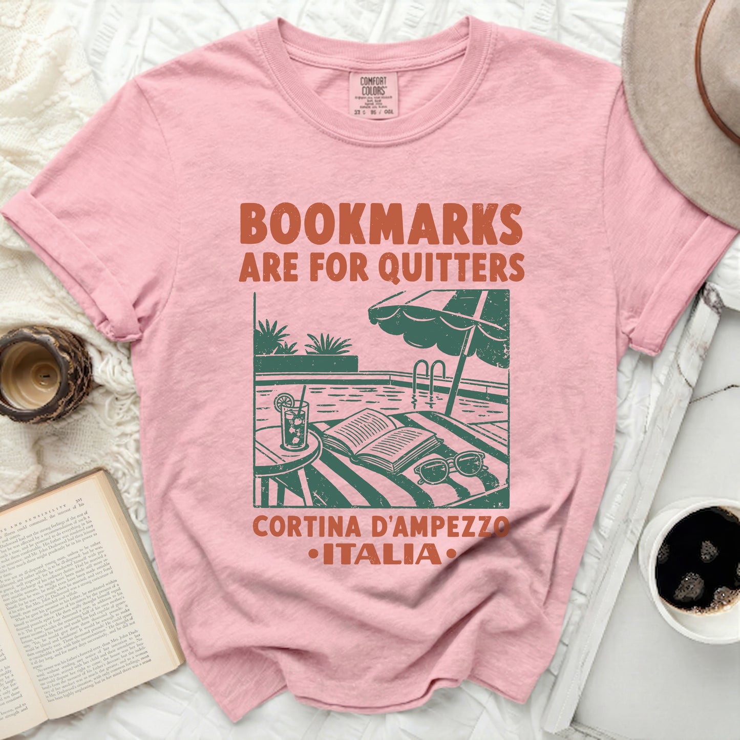Pink t-shirt with "BOOKMARKS ARE FOR QUITTERS" and Italian town graphic.