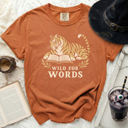 Orange t-shirt with a tiger lying on an open book, text reads "WILD FOR WORDS."