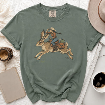 T-shirt with illustration of cowgirl riding a rabbit, wearing a hat and carrying books.