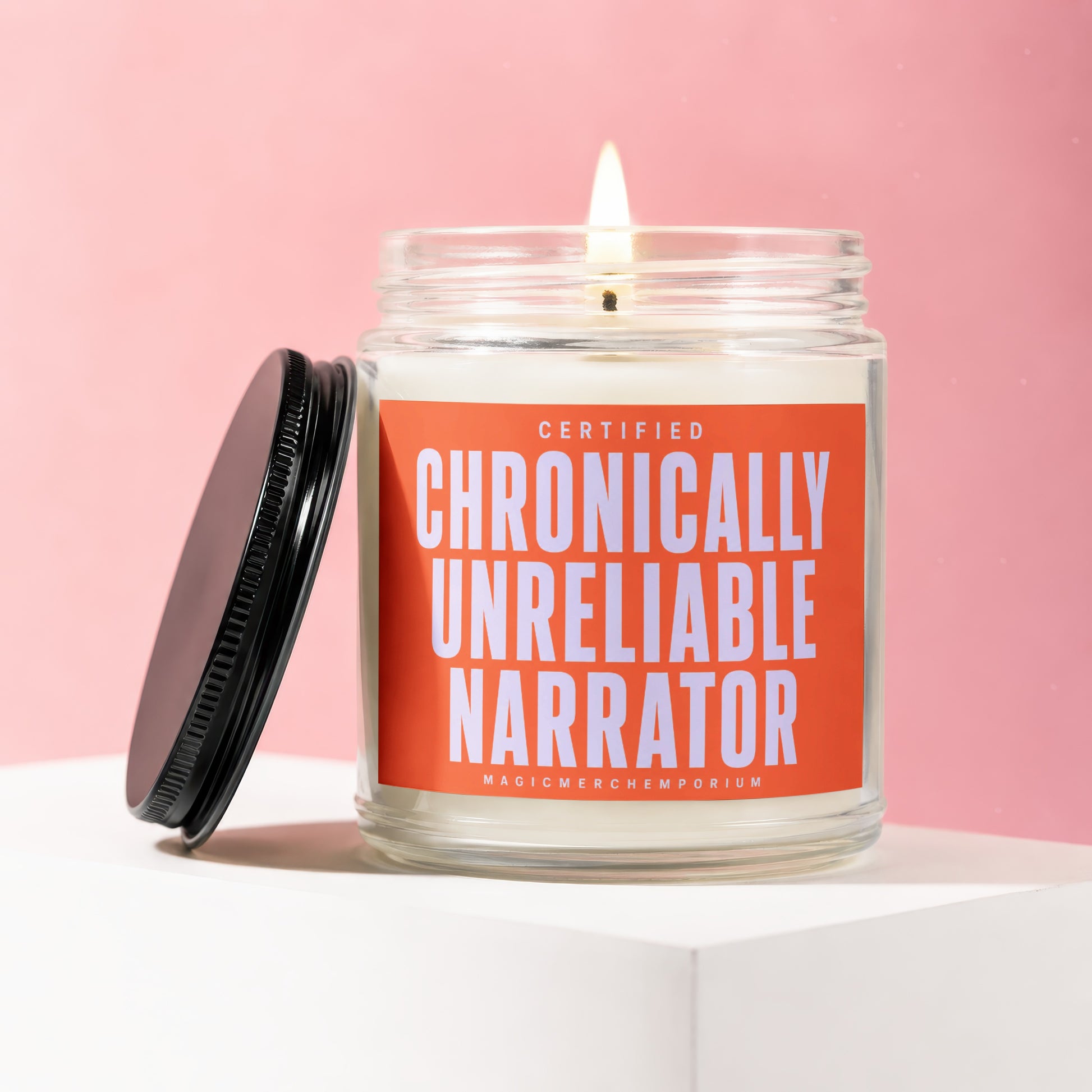 Glass jar candle with lit flame, black lid, and orange label reading "CERTIFIED CHRONICALLY UNRELIABLE NARRATOR".