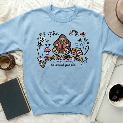 Light blue sweatshirt with Bigfoot reading a book and text "The Booksquatch reads past bedtime to avoid people".