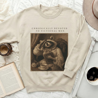 Cream sweatshirt with raccoon wearing vintage clothing and text "CHRONICALLY DEVOTED TO FICTIONAL MEN".