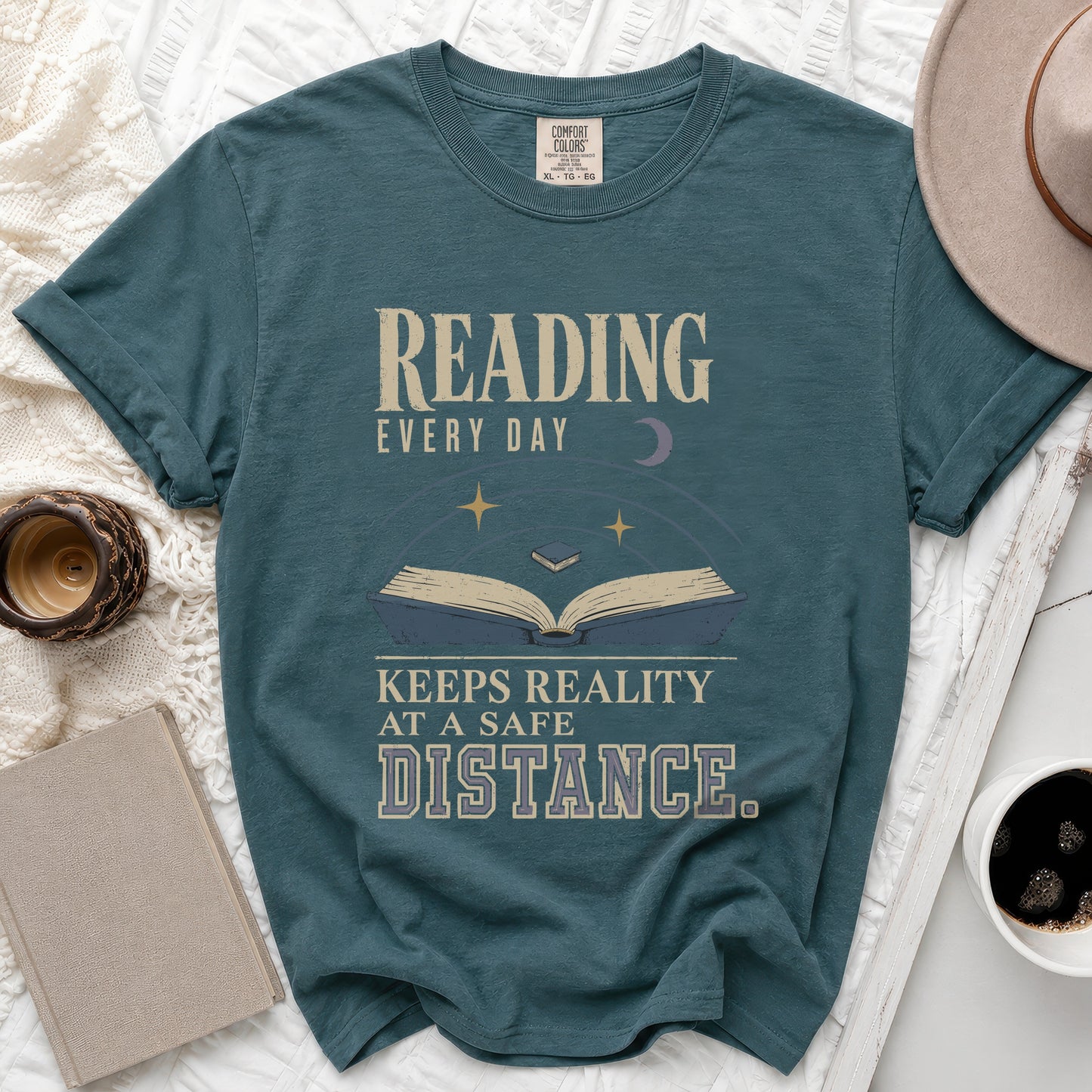 Teal t-shirt with "Reading Every Day Keeps Reality At A Safe Distance" text.