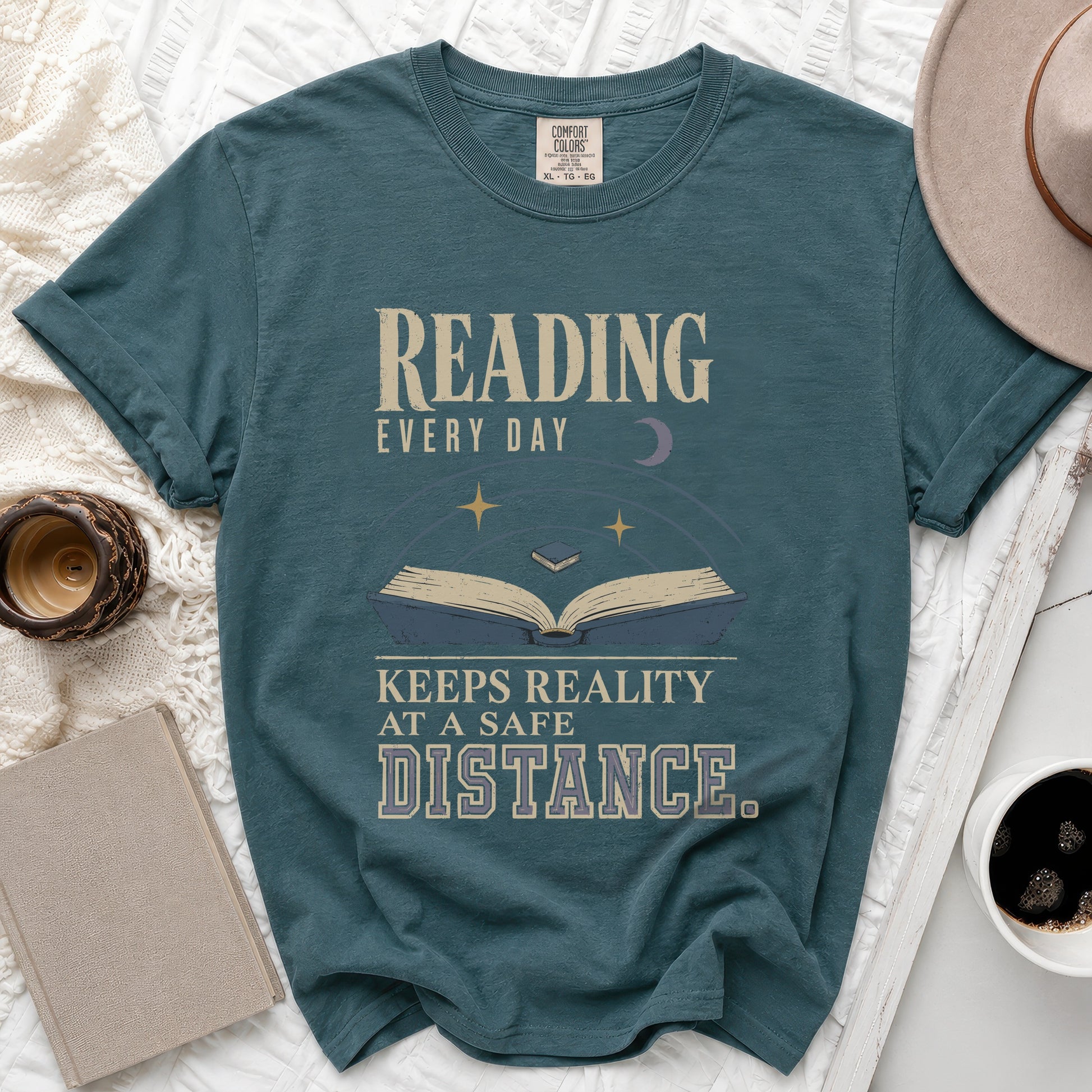 Teal t-shirt with "Reading Every Day Keeps Reality At A Safe Distance" text.