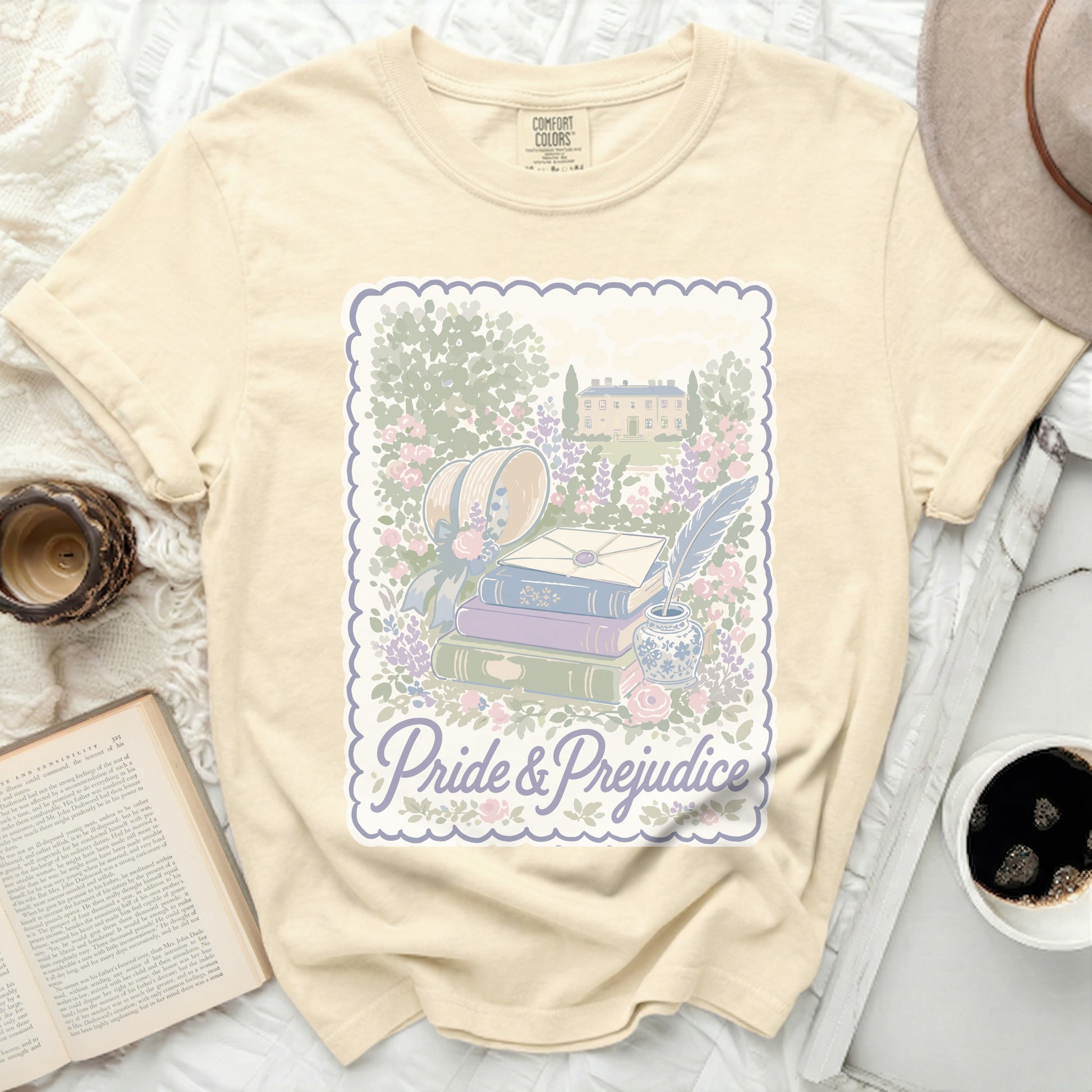 Cream t-shirt with Pride & Prejudice illustration of books and manor.