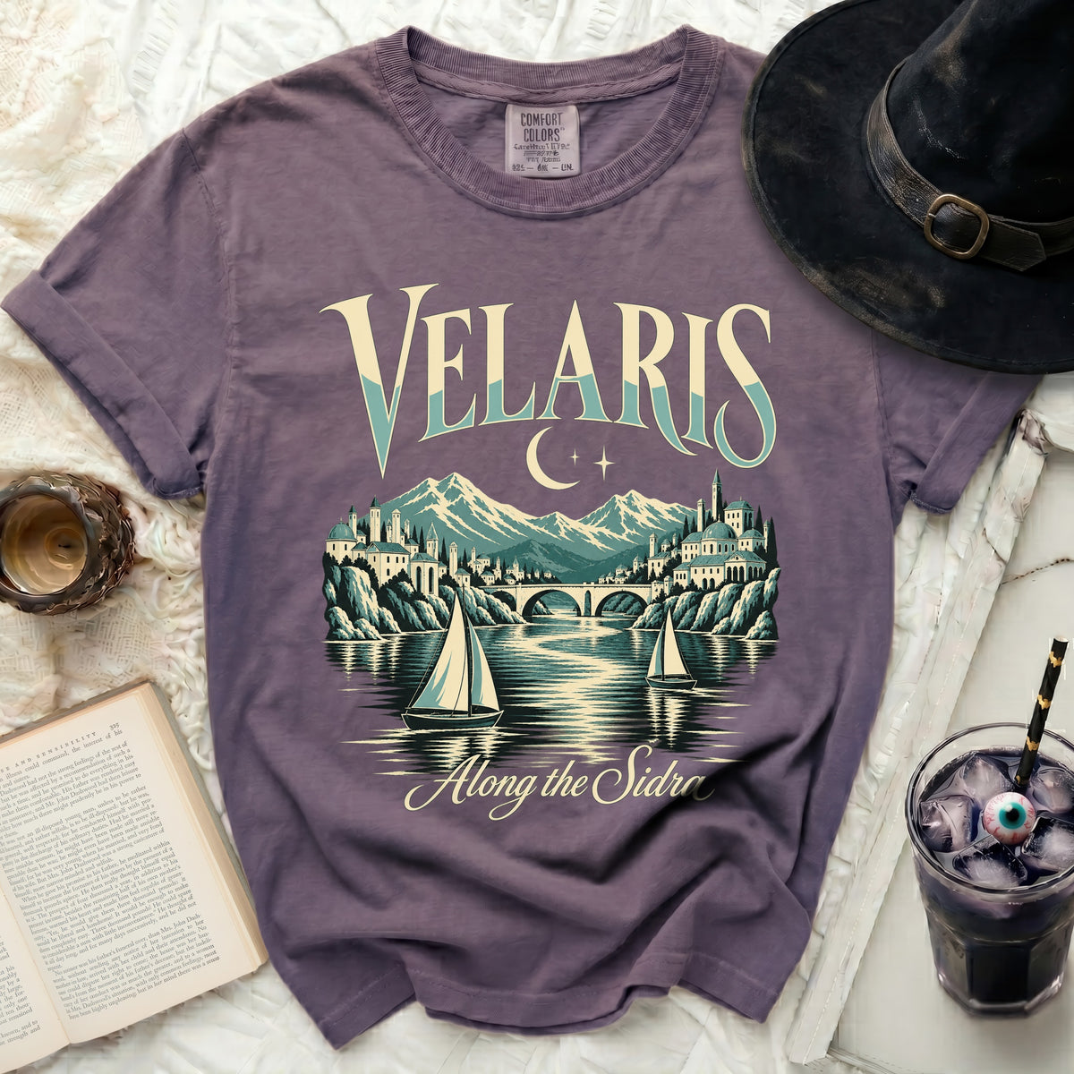 Purple t-shirt with Velaris graphic and moon, mountains, city, bridge, and sailboats.
