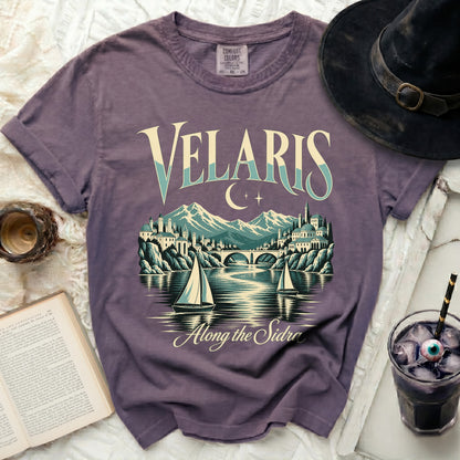 Purple t-shirt with Velaris graphic and moon, mountains, city, bridge, and sailboats.