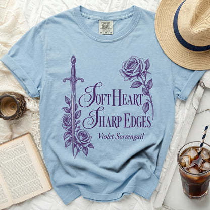 Light blue t-shirt with purple sword, rose, and "Soft Heart Sharp Edges" text.