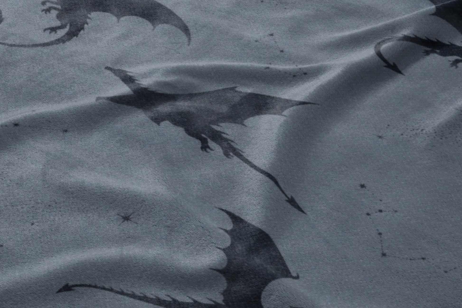 Dark dragons with wings are patterned across a rumpled grey fabric with small star details.