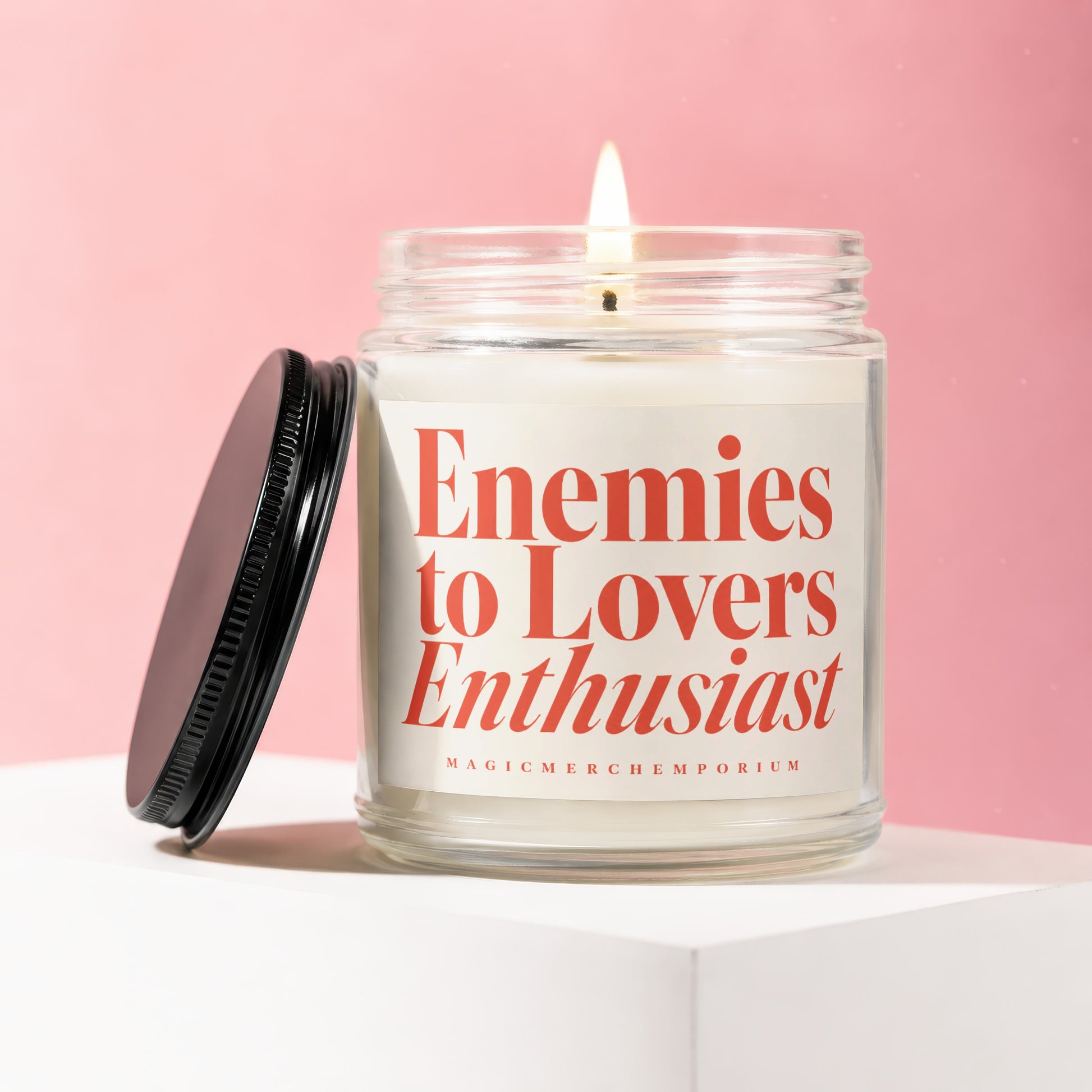 Candle with "Enemies to Lovers Enthusiast" text on label, black lid beside it.