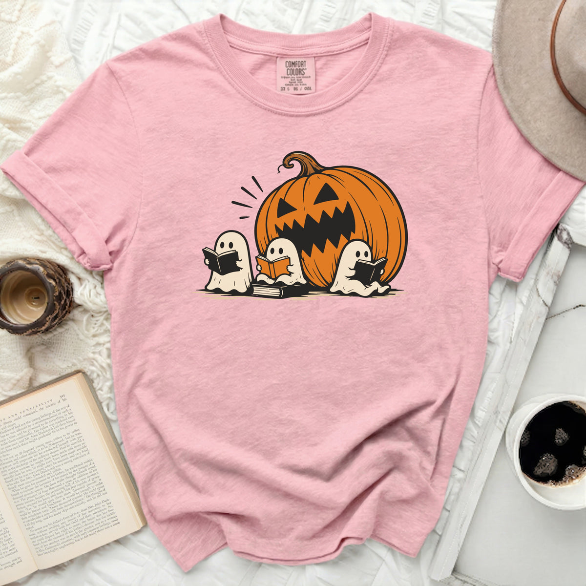 Pink t-shirt with jack-o'-lantern and three ghosts reading books graphic.