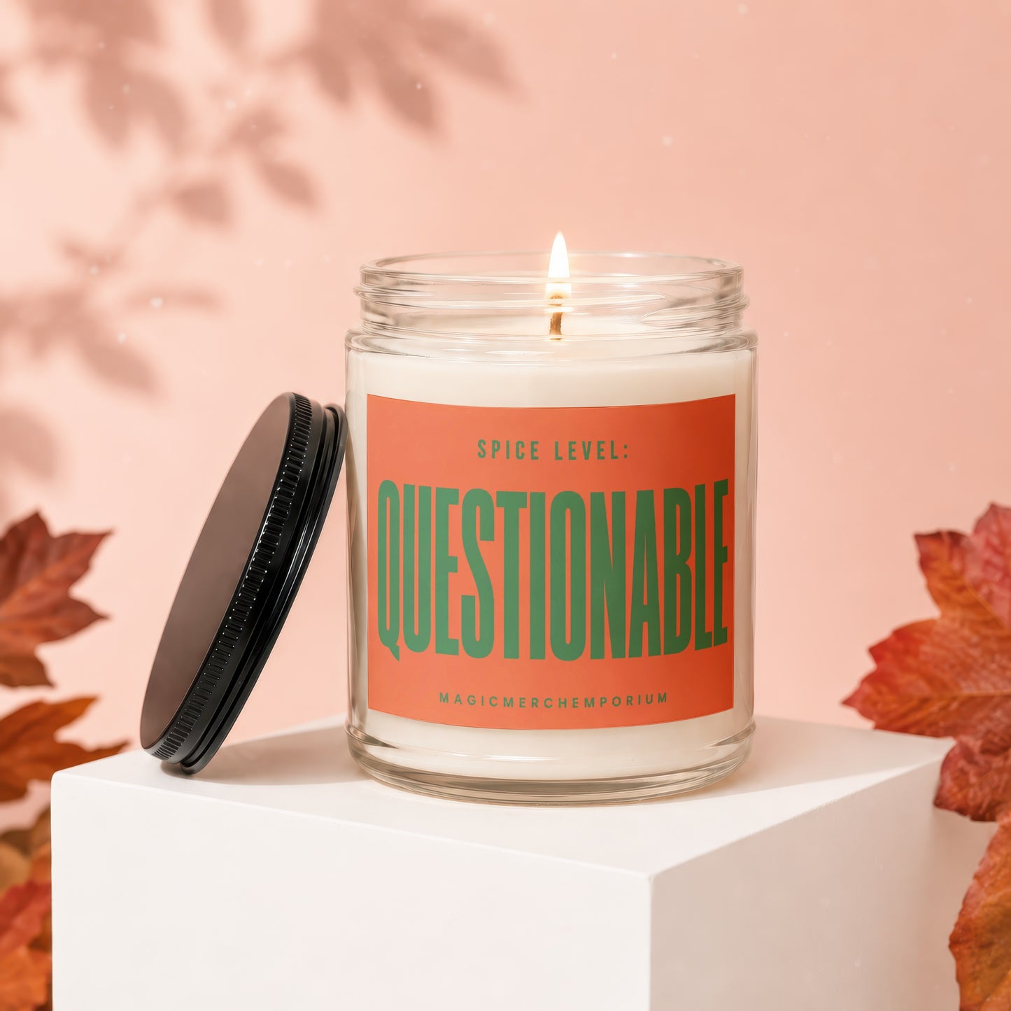 Jar candle with orange label reading "SPICE LEVEL: QUESTIONABLE" and "MAGICMERCH..."