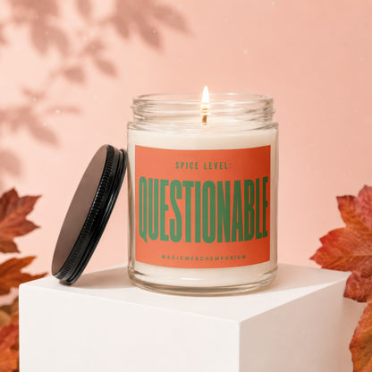 Jar candle with orange label reading "SPICE LEVEL: QUESTIONABLE" and "MAGICMERCH..."