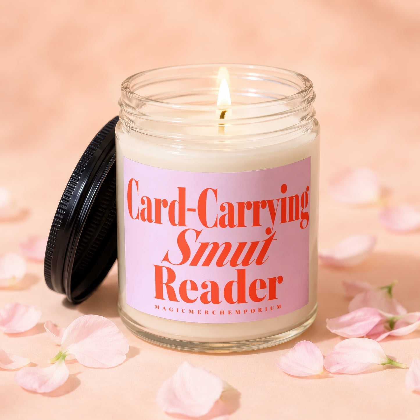 Burning candle with pink label reading "Card-Carrying Smut Reader".