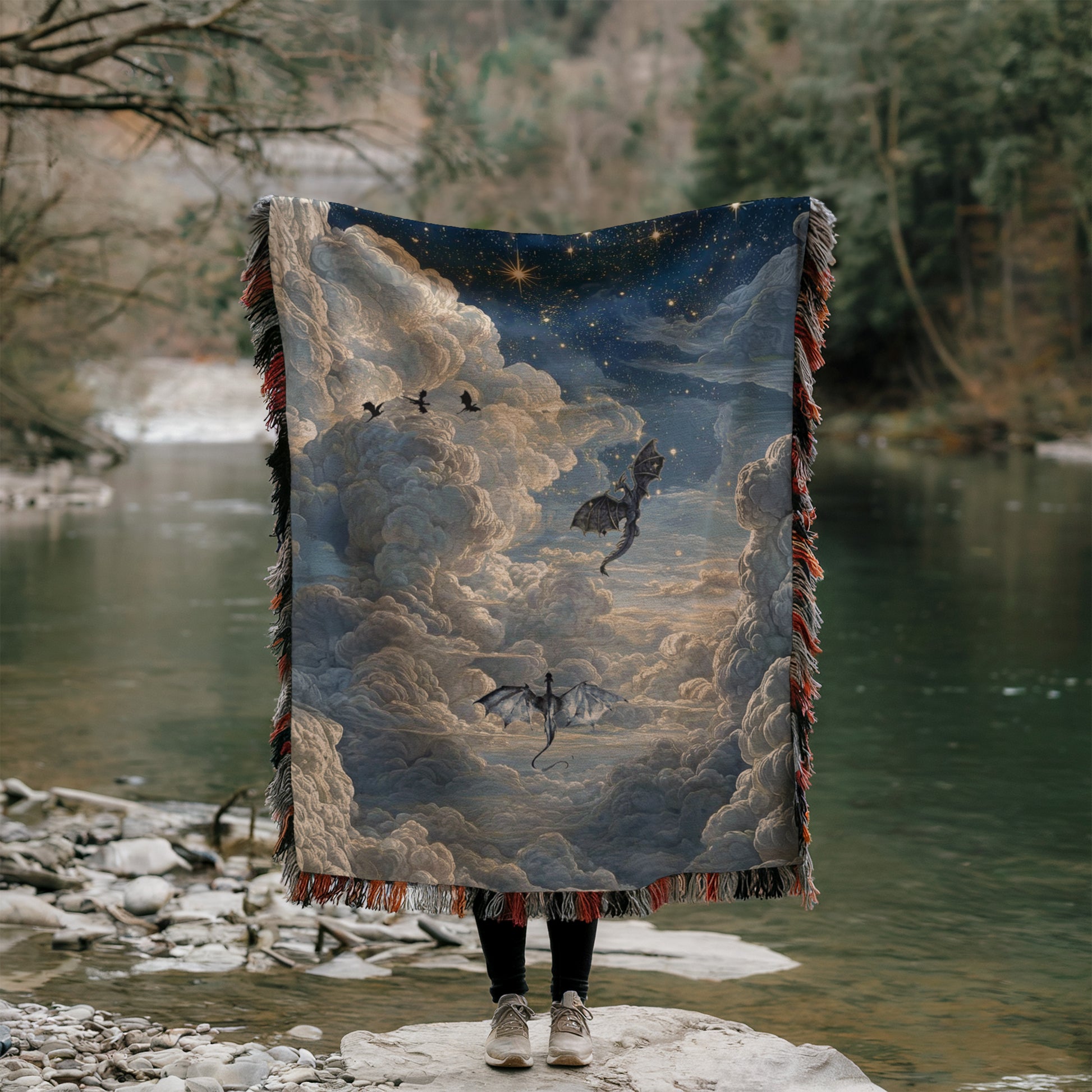 A person is standing on a rock, holding a large blanket that features a painting of a dragon flying through a starry sky.