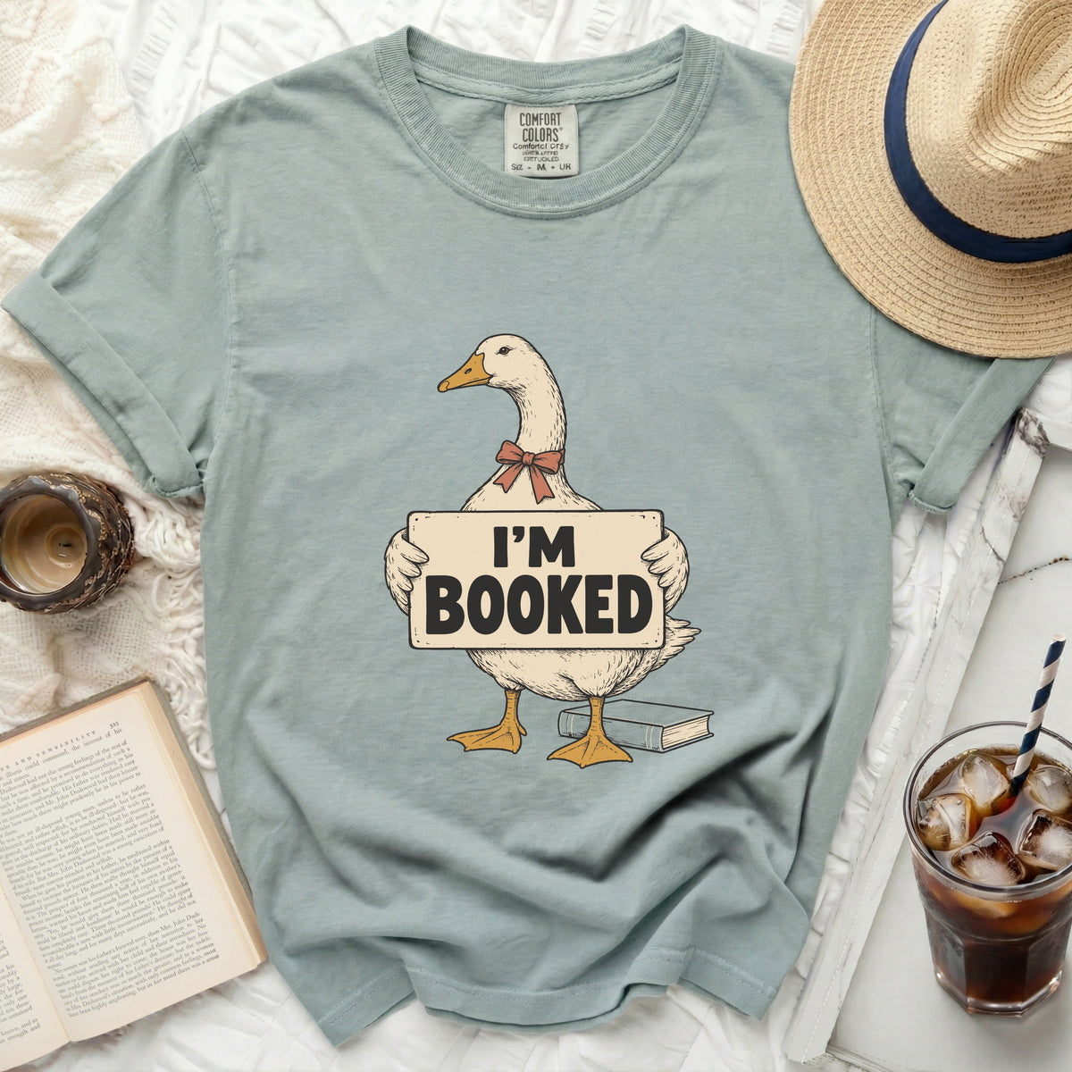 T-shirt with cartoon goose wearing bow tie and holding "I'M BOOKED" sign.