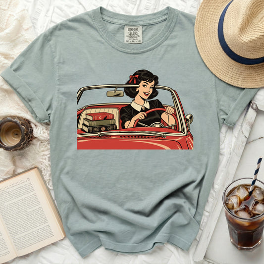 A grey-green t-shirt features a vintage-style graphic of a woman driving a red convertible.