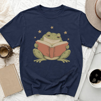 Frog reading a book with stars, on a navy t-shirt.