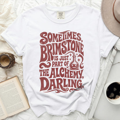 White t-shirt with "Sometimes Brimstone Is Just Part Of The Alchemy, Darling" text.