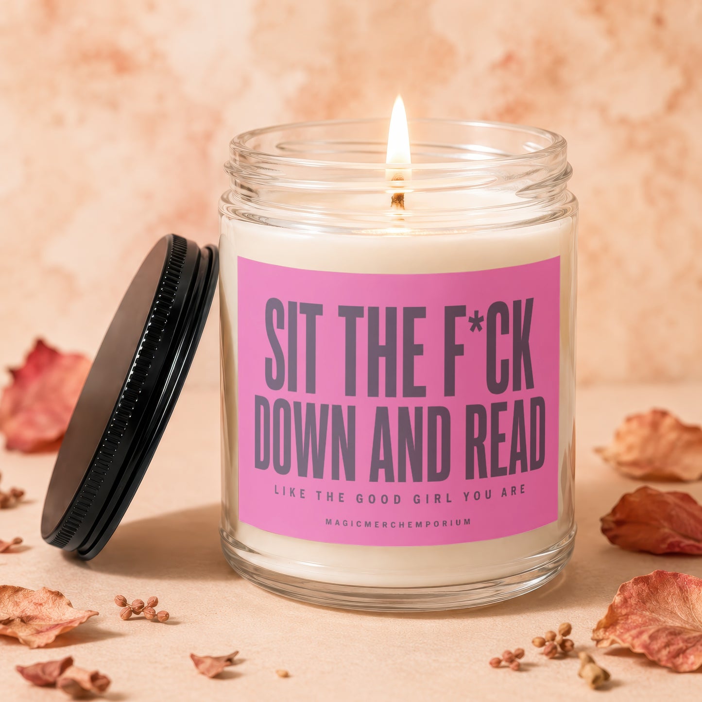 Candle with "Sit The F*CK Down and Read" text on pink label.
