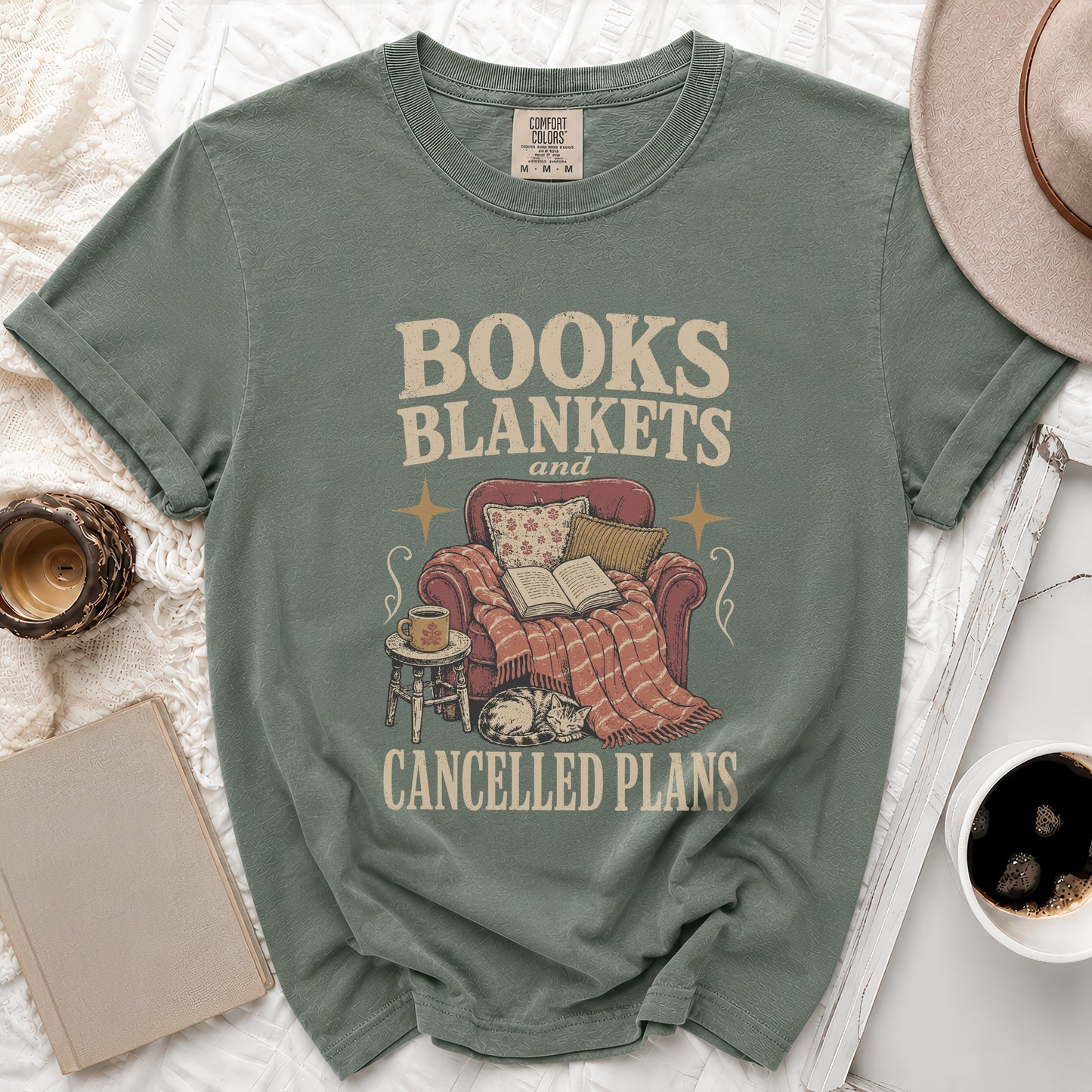 Sage green t-shirt with "Books Blankets and Cancelled Plans" text and vintage graphic.
