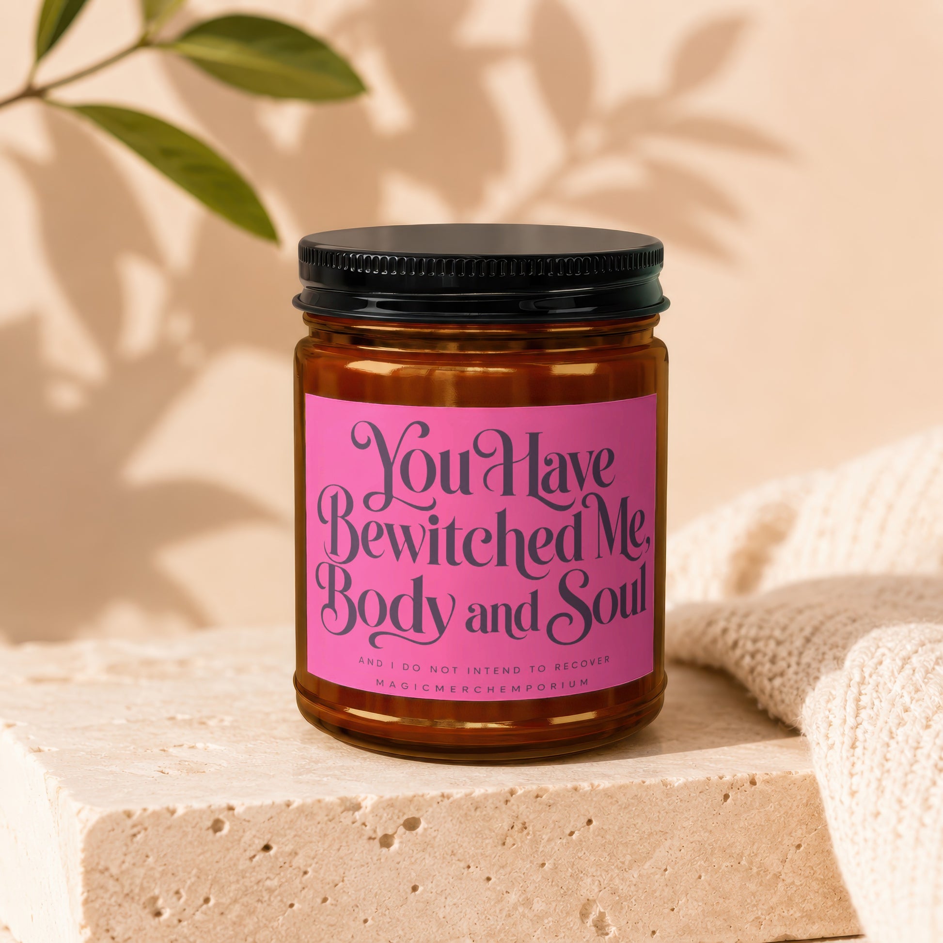 Brown glass candle with pink label reading "You Have Bewitched Me, Body and Soul."